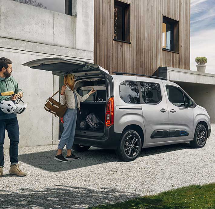 coffre ouvert citroen berlingo avec homme et femme recuperant des affaires de sport